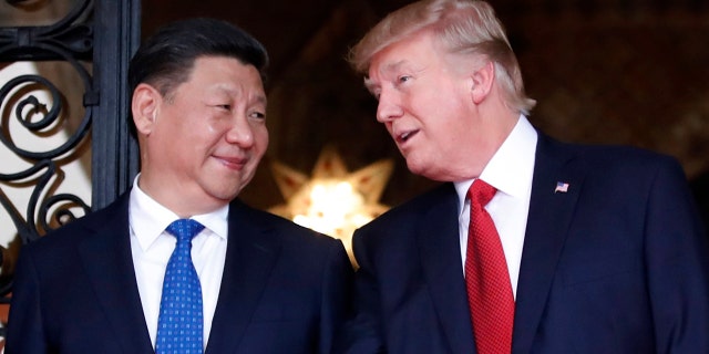 In this April 6, 2017 file photo, Chinese President Xi Jinping, left, smiles at U.S. President Donald Trump as they pose together with their wives for photographers before dinner at Mar-a-Lago in Palm Beach, Fla.