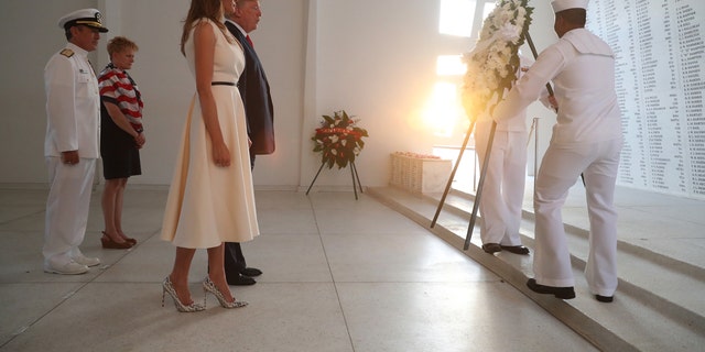 President Donald Trump and first lady Melania Trump watch as a wreath is positioned at the USS Arizona Memorial at Pearl Harbor, Hawaii, Nov. 3, 2017.
