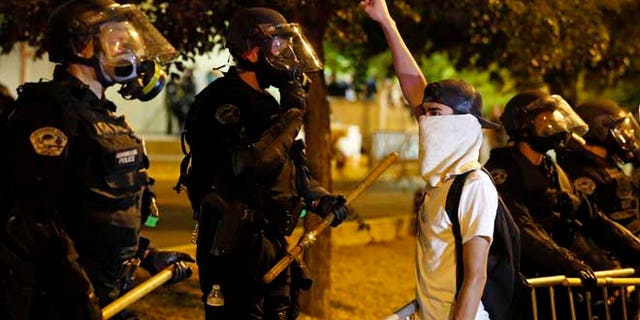 FILE - In this May 24, 2016, file photo, riot police block off the Albuquerque Convention Center to anti-Trump protests following a rally and speech by Republican presidential candidate Donald Trump at the convention center where the event was held, in Albuquerque, N.M. Activists say peaceful protesters have been unfairly targeted by Albuquerque police who announced they were searching for suspects connected to the demonstration that turned violent. (AP Photo/Brennan Linsley, File)