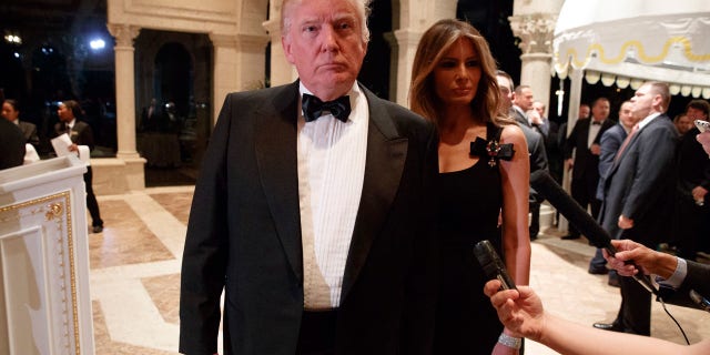 Melania Trump, right, looks on as her husband President-elect Donald Trump talks to reporters during a New Year's Eve party at Mar-a-Lago, Saturday, Dec. 31, 2016, in Palm Beach, Fla. (AP Photo/Evan Vucci)