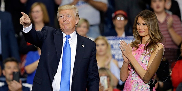 President Donald Trump points to supporters as first lady Melania Trump looks on after speaking at the Covelli Center, Tuesday, July 25, 2017, in Youngstown, Ohio.  (AP Photo/Tony Dejak)
