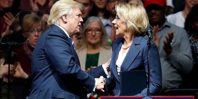 President-elect Donald Trump shakes hands with his pick for Education Secretary Betsy DeVos during a rally, in Grand Rapids, Mich., Friday, Dec. 9, 2016.