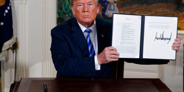 President Donald Trump shows a signed Presidential Memorandum after delivering a statement on the Iran nuclear deal from the Diplomatic Reception Room of the White House, Tuesday, May 8, 2018, in Washington. (AP Photo/Evan Vucci)