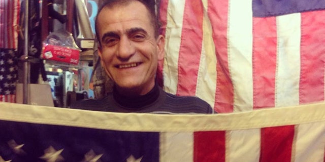 A man poses behind American Flag-themed display at a bazaar in Kurdish territory, where America and Donald Trump are popular.