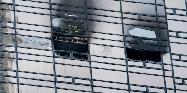 A firefighter looks out from the window of a fire damaged apartment in Trump Tower in New York on Saturday, April 7, 2018.