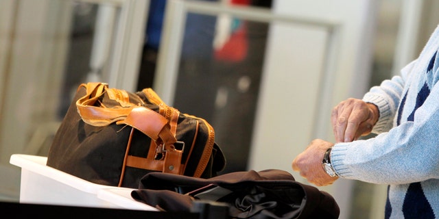 An airline passenger removes his watch before being screened at a security checkpoint.