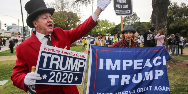 Gregg Donovan, left, supporter of President Donald Trump holds a sign during a rally against a visit by President Donald Trump, March 13, 2018.