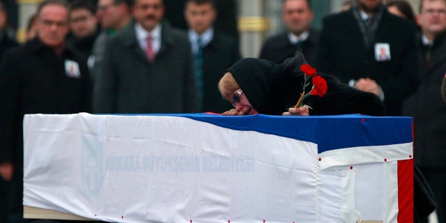 The wife of Russian Ambassador to Turkey Andrei Karlov who was assassinated Monday, cries over her husband's coffin, draped in the Russian flag, during a ceremony at the airport in Ankara, Turkey, Tuesday, Dec, 20, 2016. (AP Photo/ Emrah Gurel)
