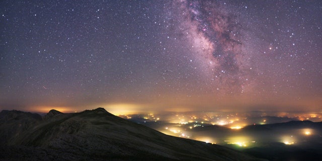 A view from the Uludag National Park in Turkey. The Milky Way stretches across the sky above the manmade pockets of hazy lights from the towns and villages below.
