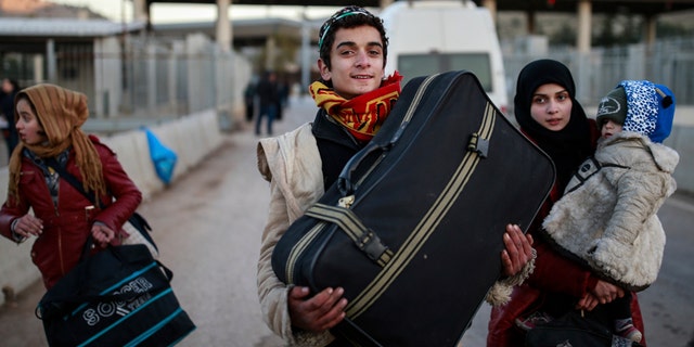 Members of a Syrian family carry their belongings after they crossed into Turkey at the Cilvegozu border gate with Syria, near Hatay, southeastern Turkey, Sunday, Dec, 18, 2016. Several people were able to cross into Turkey after they managed to leave the embattled Syrian city during the ceasefire, and arrived to Turkey by their own means. The Aleppo evacuation was suspended Friday after a report of shooting at a crossing point into the enclave by both sides of the conflict. (AP Photo/Emrah Gurel)