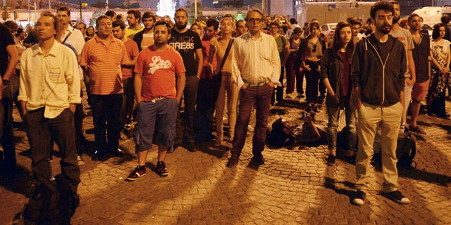 June 18, 2013: Erdem Gunduz, left, and dozens of people stand silently on Taksim Square in Istanbul, Turkey. After weeks of confrontation with police, sometimes violent, Turkish protesters are using a new form of resistance: standing silently. The development started late Monday when a solitary man began standing in passive defiance against Prime Minister Recep Tayyip Erdogan's authority at Istanbul's central Taksim Square.