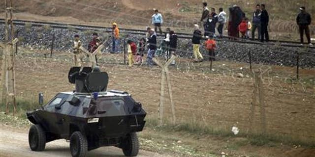 A Turkish soldier speaks with Syrian refugees who are trying to cross the border fence from the northern Syrian town of Ras al-Ain into Turkey.