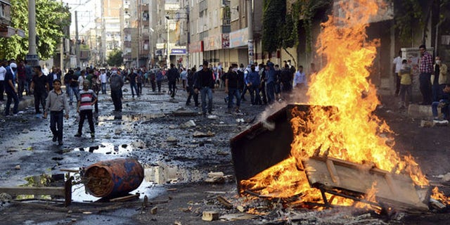 Kurdish protesters set fire to a barricade set up to block the street as they clash with riot police in Diyarbakir, Turkey. (Reuters)