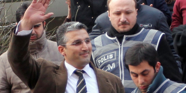 Nedim Sener, a leading investigative reporter of daily newspaper Milliyet, waves after police detained him in Istanbul, Turkey, Thursday, March 3, 2011. Police detained about 10 people, mostly journalists, including Sener, in a crackdown on an alleged secularist network accused of conspiring to topple the Islamic-rooted government, reports said. Critics say the case is part of a government assault on press freedom.
