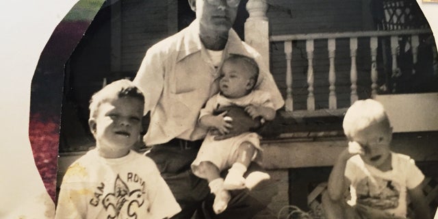 In an old photograph, Francis Turner poses with his three sons, each diagnosed with Down syndrome.