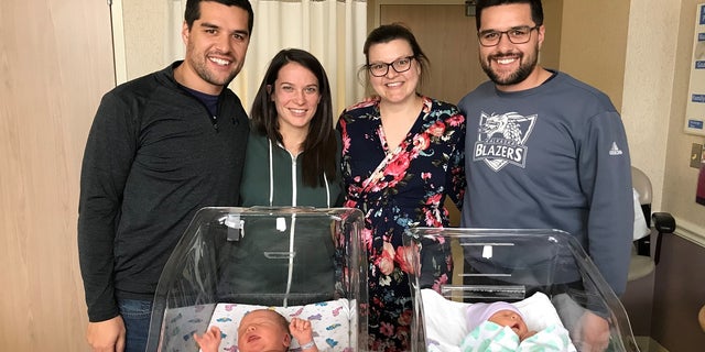 From left to right: Josh, Denise, Alex and Justin pose with their newborns for a photo.