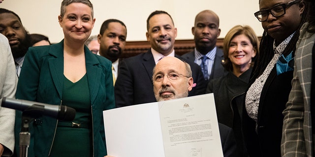 Pennsylvania Gov. Tom Wolf displays his signature after vetoing a bill passed by the Republican-controlled Legislature to limit abortions to the first 20 weeks of pregnancy at City Hall in Philadelphia, Monday, Dec. 18, 2017.