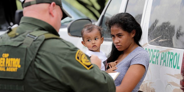 A mother migrating from Honduras holds her 1-year-old child as surrendering to U.S. Border Patrol agents after illegally crossing the border near McAllen, Texas.