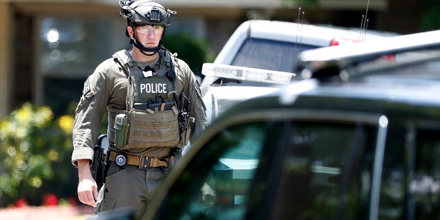State and federal law enforcement officers in tactical gear work outside a home in Alvin, Texas, as part of the investigation in the aftermath of a deadly shooting at Santa Fe High School.