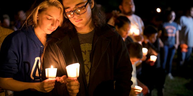 Bailey LeJeaune, 17, and David Betancourt, 18, hold candles during a vigil in Sutherland Springs for the victims of a deadly shooting at the First Baptist Church in Sutherland Springs, Texas, Sunday, Nov. 5, 2017. A man opened fire inside of the church in the small South Texas community on Sunday, killing more than 20 people. (Jay Janner/Austin American-Statesman via AP)