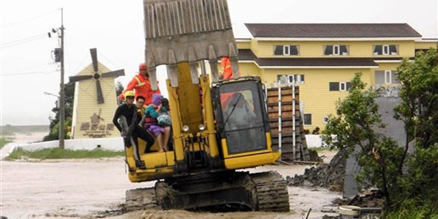 In this photo released by Hengchun Township Fire Department, residents are evacuated on an excavator as Typhoon Nanmadol began blowing toward Taiwan in Hengchu township, Pingtung county, southern Taiwan, Sunday, Aug. 28, 2011.