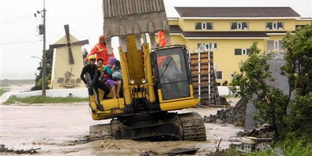 In this photo released by Hengchun Township Fire Department, residents are evacuated on an excavator as Typhoon Nanmadol began blowing toward Taiwan in Hengchu township, Pingtung county, southern Taiwan, Sunday, Aug. 28, 2011.