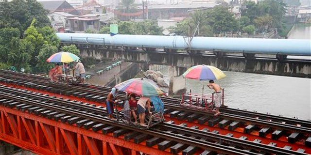 Oct. 17, 2015: Commuters ride on a locally-built cart known as "trolley" which makes use of a railroad track on a typhoon-induced rain in Manila, Philippines.