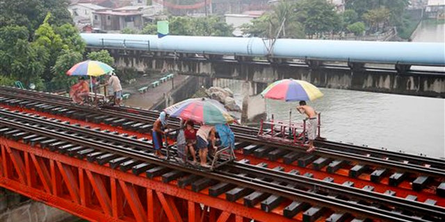Oct. 17, 2015: Commuters ride on a locally-built cart known as "trolley" which makes use of a railroad track on a typhoon-induced rain in Manila, Philippines.