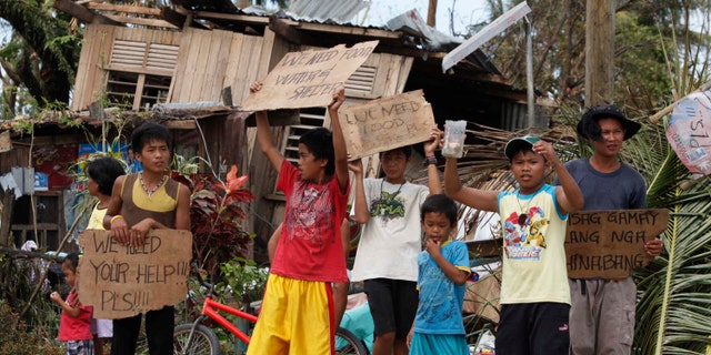 Children hold signs asking for help and food along the highway, after Typhoon Haiyan hit Tabogon town in Cebu Province, central Philippines November 11, 2013. (REUTERS/Charlie Saceda)