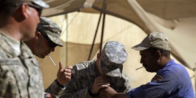 In this photo taken Wednesday, March 16, 2011, an Iraqi Army soldier, right, lights a cigarette for U.S. Army Sgt. Brett Lester, center, of Riverside, Calif. , from D Co. , 1st Battalion, 18th Infantry Regiment, 2nd Brigade, 1st Infantry Division, during training on M1A1 Abrams tanks at Camp Taji, north of Baghdad, Iraq. (AP)