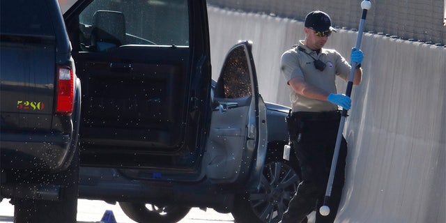 June 1, 2018: A Denver Police Department technician investigates the scene where a Nissan sedan, background center, being driven by an Uber driver crashed into a retaining wall along Interstate 25 south of downtown Denver early Friday.