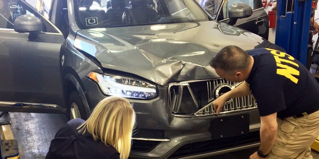 March 20, 2018, photo provided by the National Transportation Safety Board, investigators examine a driverless Uber SUV that fatally struck a woman in Tempe, Ariz.