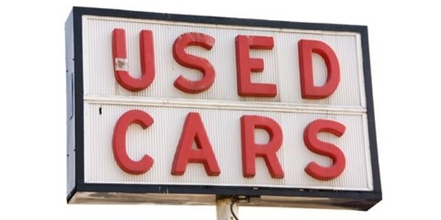 This is a picture of an old used cars sign with red letters, isolated on a white background.
