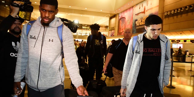 UCLA basketball players Cody Riley (left), LiAngelo Ball (right), and Jalen Hill (background center), are surrounded by the media as they leave the Los Angeles International Airport.