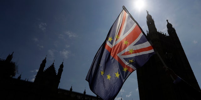 A flag is waved by a pro-EU demonstrator outside Parliament in London, Wednesday, June 13, 2018. The British government is bracing for more bruising debate on its key Brexit bill, after being forced to give ground to pro-EU lawmakers to avoid defeat.(AP Photo/Kirsty Wigglesworth)