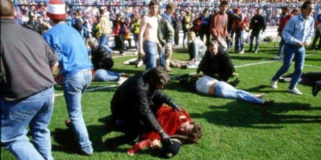 FILE - In this April 15, 1989 file photo, showing police, stewards and supporters as they tend to wounded soccer supporters on the field at Hillsborough Stadium, in Sheffield, England. 96 Liverpool fans were crushed to death in the incident at the FA Cup semi-final match Liverpool against Nottingham Forest.