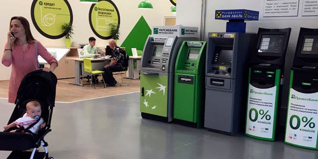 A woman passes by cash machines that do not work in a city supermarket in Kiev, Ukraine, Wednesday, June 28, 2017. The cyberattack ransomware that has paralyzed computers across the world hit Ukraine hardest Tuesday, with victims including top-level government offices, energy companies, banks, cash machines, gas stations, and supermarkets. (AP Photo/Efrem Lukatsky)
