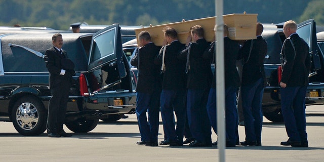 July 23, 2014: Soldiers load coffins into cars under a Ukrainian flag during a ceremony to mark the return of the first bodies, of passengers and crew killed in the downing of Malaysia Airlines Flight 17, from Ukraine at Eindhoven military air base.