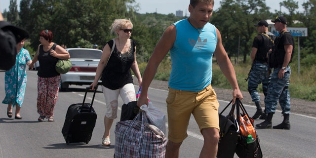 July 28, 2014: Self-proclamed Donetsk People's Republic policemen watch refugees fleeing Shakhtarsk, Donetsk region, eastern Ukraine. An international police team abandoned its attempt to reach the crash site of a Malaysia Airlines plane for a second day running Monday as clashes raged in a town on the road to the area.