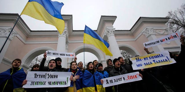 March 11, 2014: People hold Ukrainian flags and banners that read: "Putin! Take away the green men", "They got me married without me being there", "Referendum is a step to war", during a rally against the breakup of the country in Simferopol, Crimea, Ukraine.