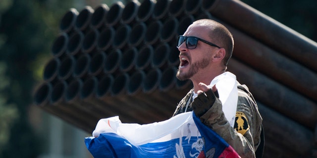Aug. 24, 2014: A pro-Russian rebel holds a Russian national flag near to damaged heavy hardware from the Ukrainian army during an exhibition in the central square in Donetsk, eastern Ukraine. (AP/Antoine E.R. Delaunay)