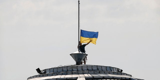 A climber installs the Ukrainian national flag on a roof, marking the Day of the State Flag, on the eve of the Independence Day, in Kiev, Ukraine, Aug. 23, 2016. (REUTERS/Gleb Garanich)