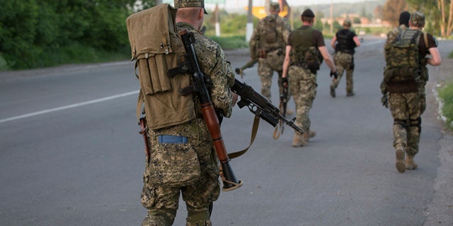 May 17, 2014: Pro-Russian militants walk to their positions to fight against Ukrainian government troops at a checkpoint blocking the major highway which links Kharkiv, outside Slovyansk, eastern Ukraine.