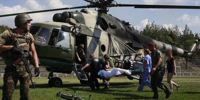 Ukrainian soldiers evacuate a wounded comrade close to Luhansk, eastern Ukraine, Thursday, Aug. 21, 2014. The rebel stronghold 20 kilometers from the Russian border has been under siege for 19 days, lacking basic amenities like running water or electricity. (AP Photo/Petro Zadorozhnyy)