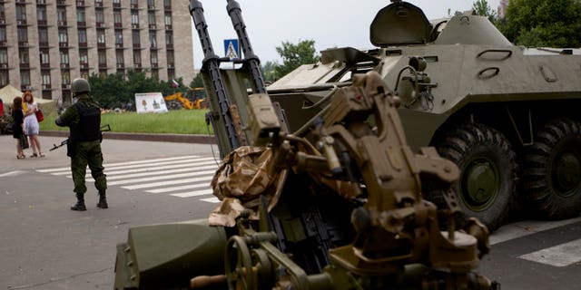 May 29, 2014: A Pro-Russian militia member guards next to an APC and anti-aircraft gun, outside the administrational building in Donetsk, Ukraine.