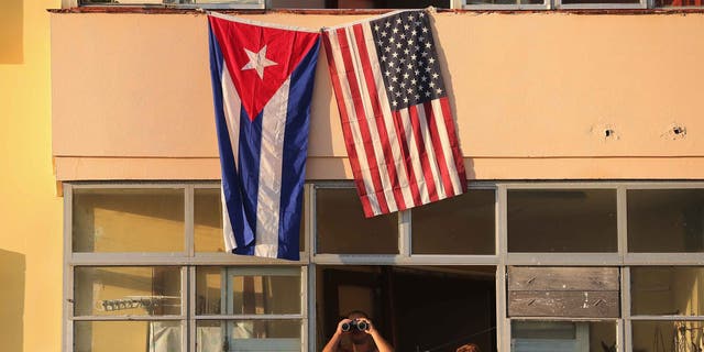 HAVANA, CUBA - AUGUST 14:  Cubans look out their window across the street from the newly reopened U.S. Embassy in hopes of watching the flag-raising ceremony August 14, 2015 in Havana, Cuba. The first American secretary of state to visit Cuba since 1945, Secretary of State John Kerry visited the reopened embassy, a symbolic act after the the two former Cold War enemies reestablished diplomatic relations in July.  (Photo by Chip Somodevilla/Getty Images)