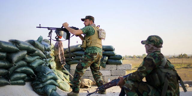 March 21, 2015: A volunteer fighter with a Shiite militant group aims his weapon during clashes with Islamic State group militants, outside Tikrit.