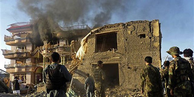 July 2: Afghan security force members stand outside a USAID compound in Kunduz, northern Afghanistan, after it was stormed by militants wearing suicide vests. Six suicide bombers attacked the compound Friday, killing at least four people and wounding several others, officials said.