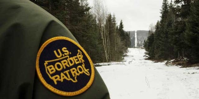 BEECHER FALLS, VT - MARCH 23: A U.S. Border Patrol agent stands along the boundary marker cut into the forest marking the line between Canadian territory on the right and the United States March 23, 2006 near Beecher Falls, Vermont. As American politicians continue to debate immigration reform, Border Patrol agents work the northern border to prevent illegal entry. (Photo by Joe Raedle/Getty Images)