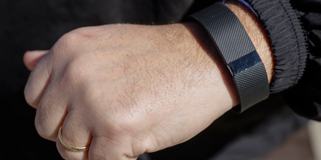 FILE - In this Monday, Feb. 29, 2016, file photo, Brett Broviak, a manager of respiratory and sleep services at IU Health North Hospital, shows off his Fitbit fitness tracker for the camera on the hospital's campus in Carmel, Ind. Wearing a stylish fitness tracker may help you keep tabs on things like how many steps you take, but the devices themselves _ even with the lure of a cash reward _ probably wonât improve your health, according to the biggest study yet done on the trendy technology. (AP Photo/AJ Mast, File)